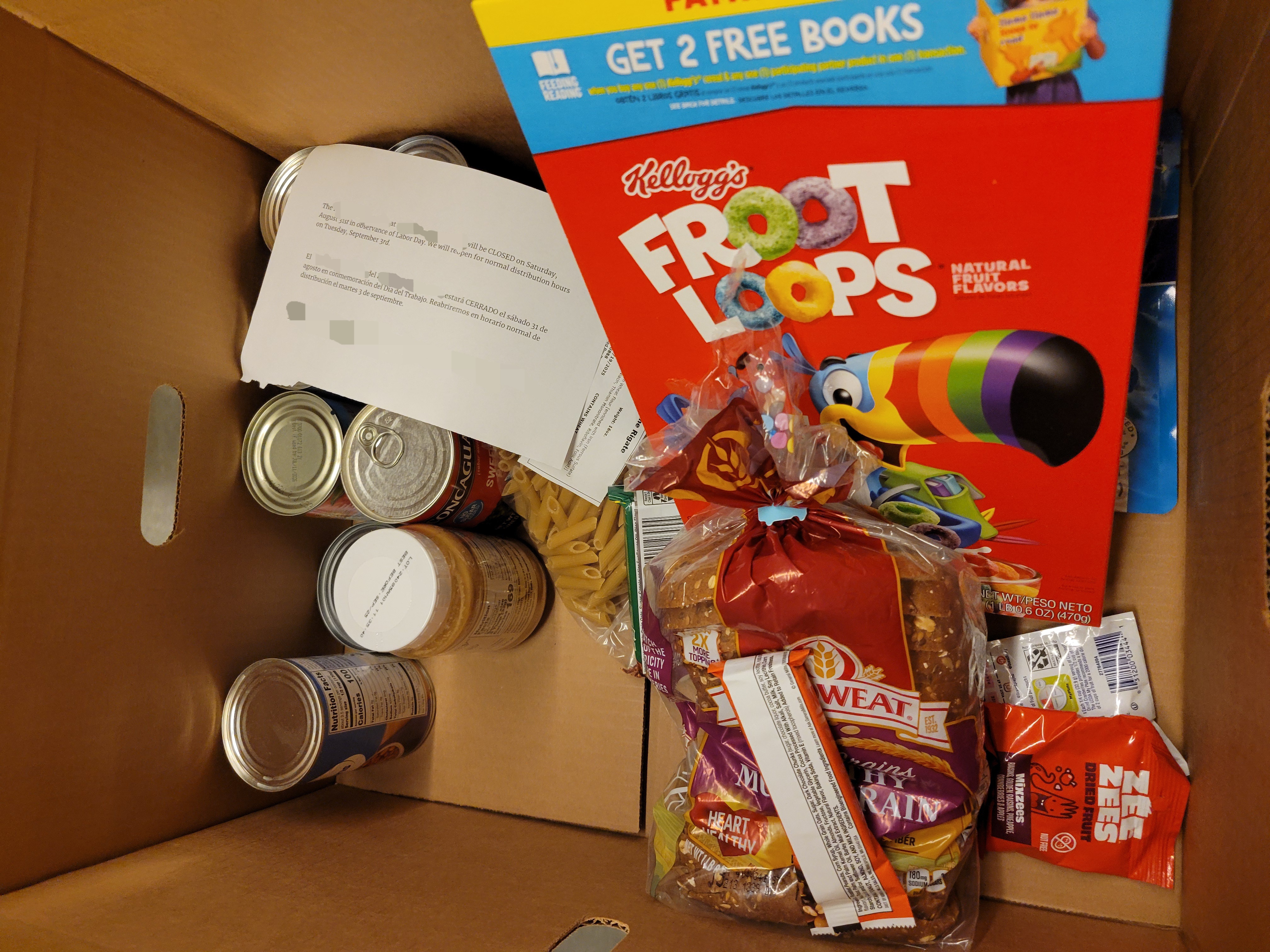 Various dry goods with a holiday closure notice in a cardboard box.